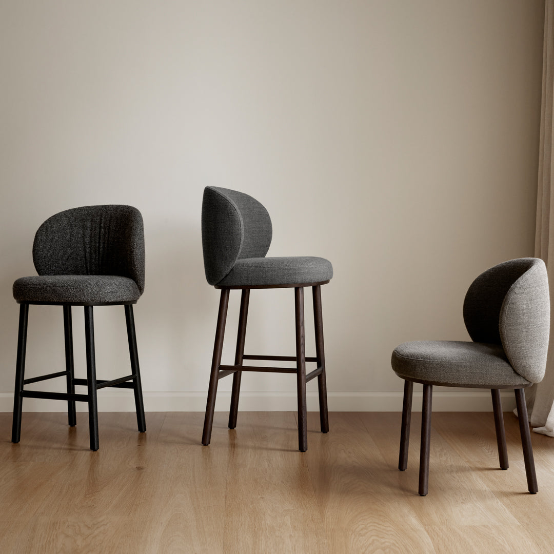 Set of three modern chairs in varying shades of gray, featuring textured upholstery and sleek wooden legs.