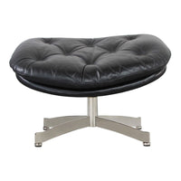 Black tufted leather ottoman with a sleek chrome base, featuring a unique kidney-shaped design for modern decor.