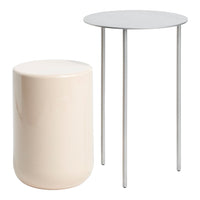 Modern round table with a sleek white top and minimal silver legs, paired with a soft beige cylindrical stool.