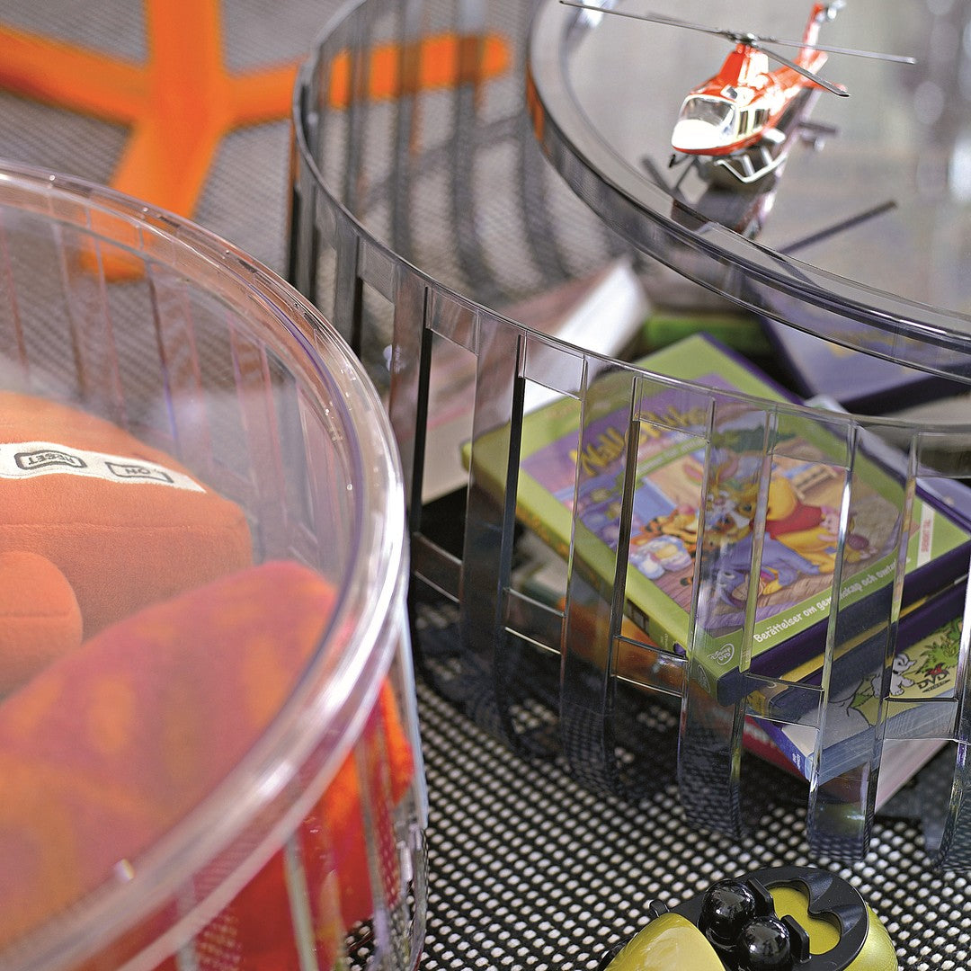 Colorful round baskets with transparent sides, featuring orange, pink, and green patterns, containing toys and books.