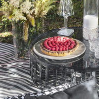 "Striking striped black and white tablecloth with elegant glassware, featuring a colorful raspberry tart centerpiece."