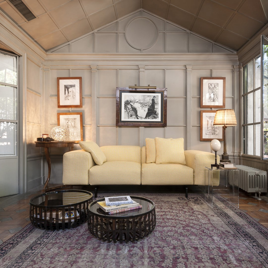 Yellow checkered sofa on a vintage patterned rug, complemented by dark wood and glass coffee tables.