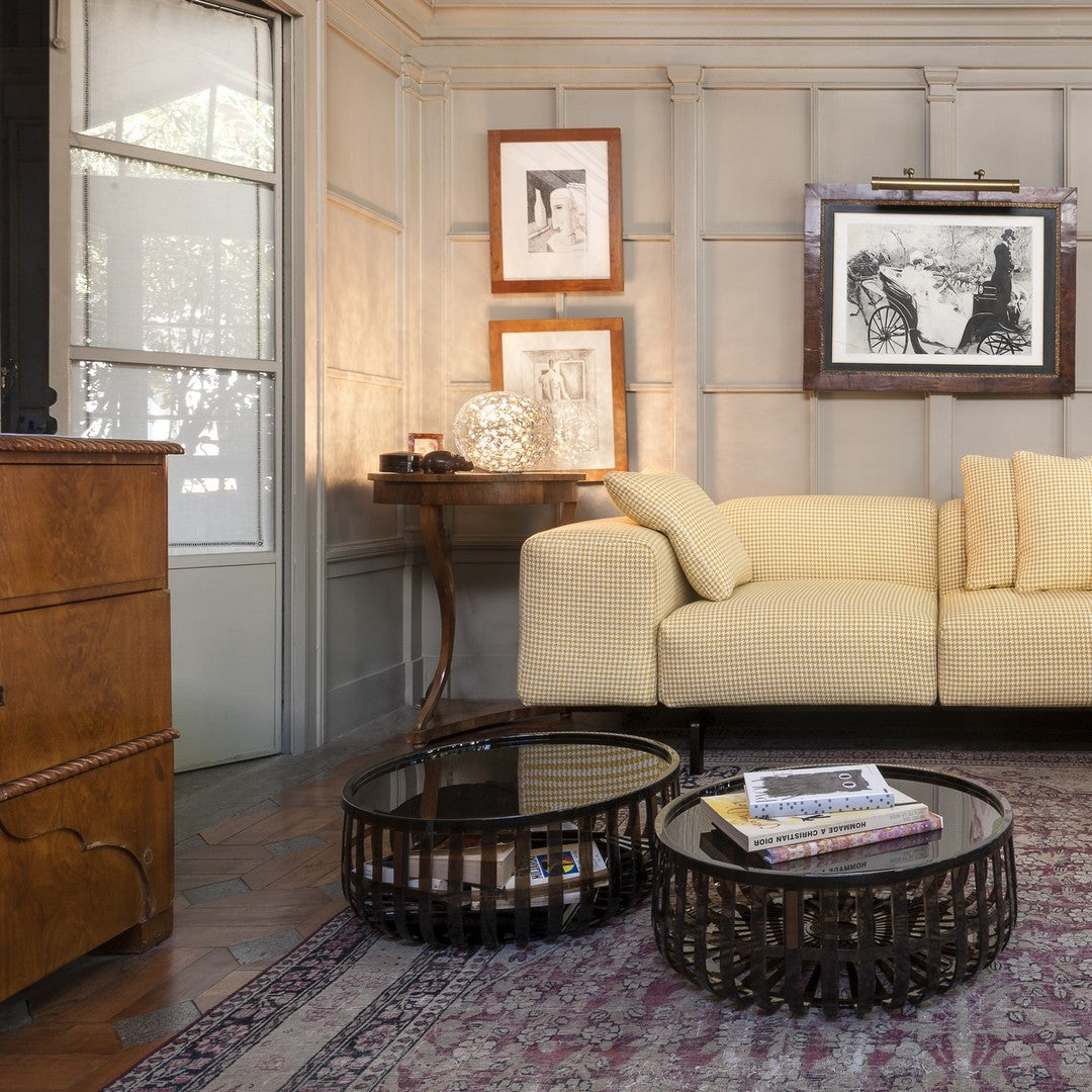 Yellow checkered sofa with dark wood accents, round black glass coffee tables, and a muted purple rug pattern.
