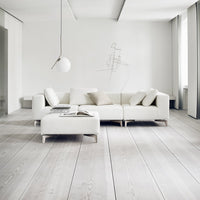 "Modern white sectional sofa with soft cushions and a light wood floor, creating a minimalist and airy aesthetic."