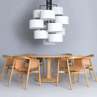 Modern dining set featuring light wood tones, cream-colored chairs, and a sleek white lamp against a gray backdrop.