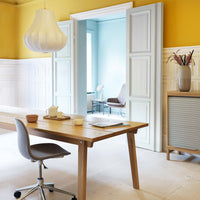 Bright yellow walls, light blue accents, white paneling, and a natural wood table create a modern, inviting workspace.