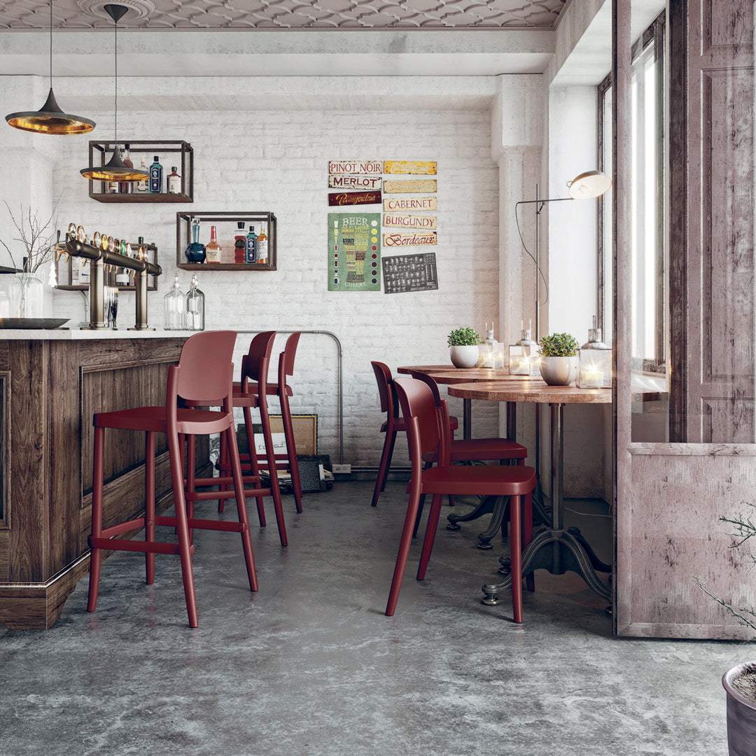 "Modern bar with red chairs and wood accents, featuring a neutral-toned floor and light-colored walls."