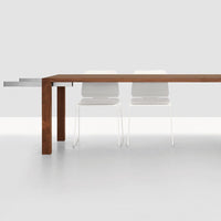 Modern wood dining table with a rich brown finish and minimalist white chairs against a sleek gray background.