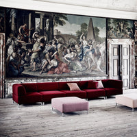 "Deep red sectional sofa with a sleek, modern design against a vintage mural backdrop; minimalist pink accent cushions."