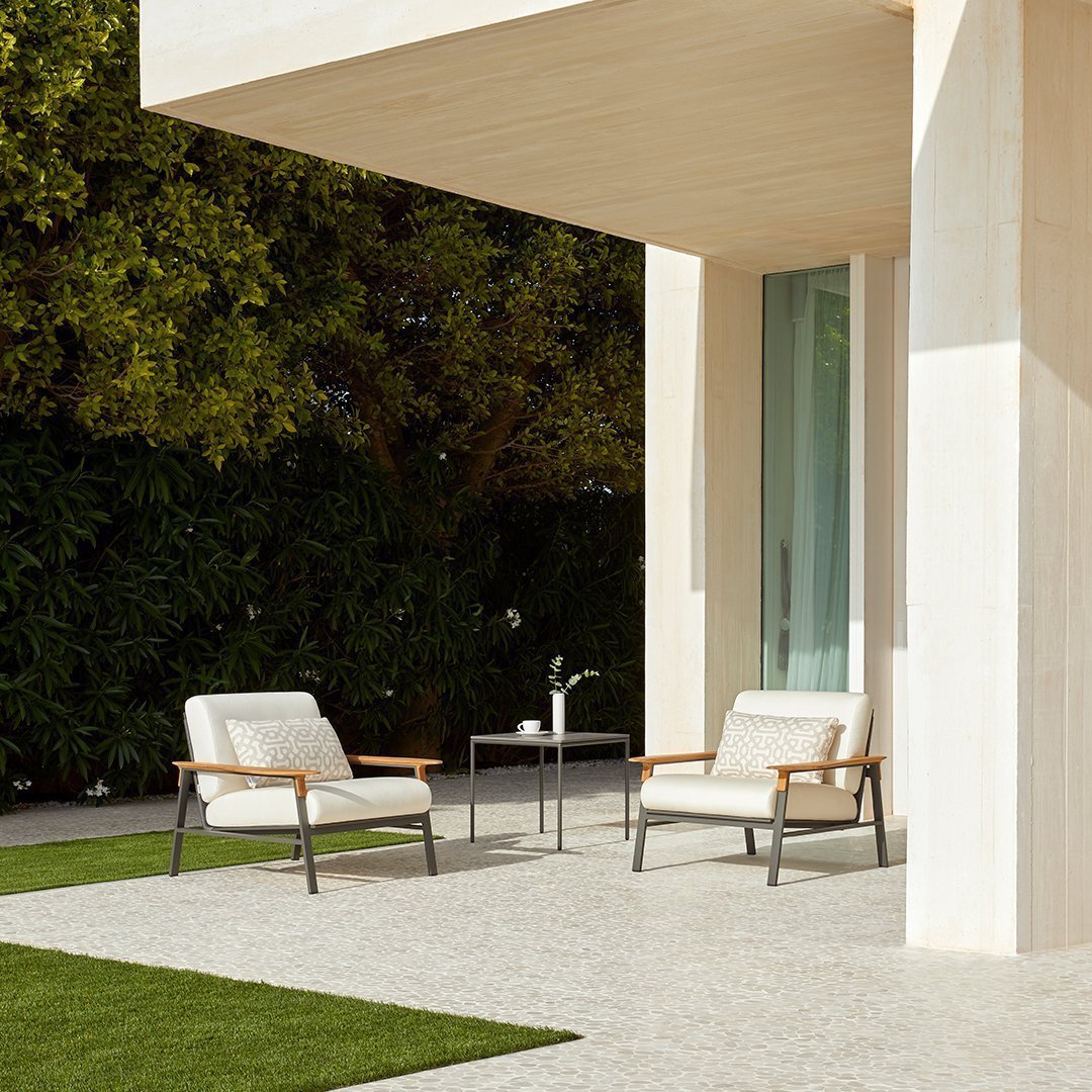 Neutral beige patio chairs with sleek gray frames, set against a green lawn and natural outdoor backdrop.