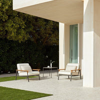 Neutral beige patio chairs with sleek gray frames, set against a green lawn and natural outdoor backdrop.