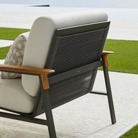 Modern outdoor chair with gray and white cushions, featuring sleek dark gray metal and natural wood accents.