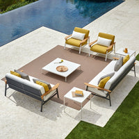 Modern patio furniture set featuring gray and white cushions, bright yellow accents, and a geometric brown rug.