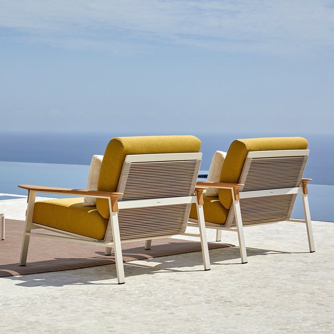 Yellow and beige padded outdoor chairs with wood accents against a serene blue ocean backdrop.