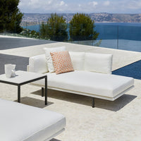 White outdoor lounge chair with a coral patterned cushion, set against a serene blue ocean view.