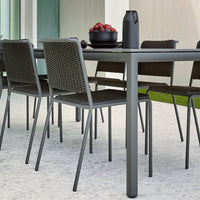 "Modern outdoor dining set featuring sleek gray chairs and table with a textured pattern, complemented by a black pitcher."