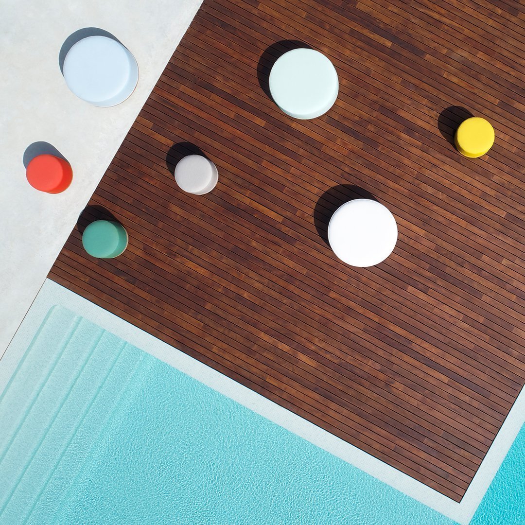 Colorful circular elements in red, blue, yellow, green, and white, set against a brown wood and aqua backdrop.