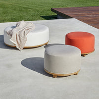 Round ottomans in white, light gray, and vibrant orange, featuring a smooth fabric finish and a subtle wooden base.