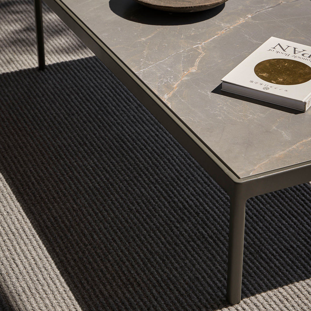 Gray marble tabletop on a modern coffee table, paired with textured gray and cream striped rug.