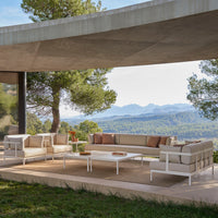 Stylish outdoor sofa set in neutral tones with subtle patterns, featuring cream and taupe cushions against a sleek white frame.