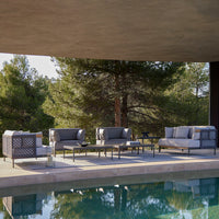 Sleek gray patio furniture with subtle geometric patterns, surrounded by green trees and a blue pool.