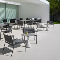 Stylish outdoor seating featuring sleek gray chairs and tables on a minimalist white patio. Perfect for modern spaces.