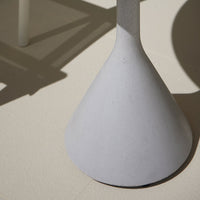Gray concrete cone base with smooth texture, casting soft shadows on a pale neutral background.