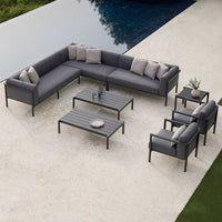 Modern gray sectional sofa with neutral cushions and sleek metal accents, set on a light stone patio by a pool.