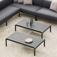 Modern black striped coffee tables with minimalist design, placed on a light textured floor, complemented by sleek decor.