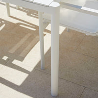 White outdoor table with clean lines and a smooth, minimalist design on a light beige tiled surface.