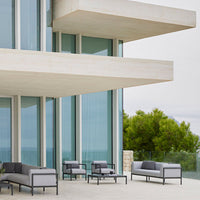Gray and black outdoor furniture with sleek lines, complemented by a modern architectural backdrop and greenery.