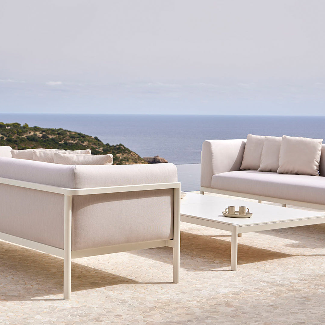 Light beige outdoor seating set with soft cushions, featuring a sleek white frame and a minimalist design.