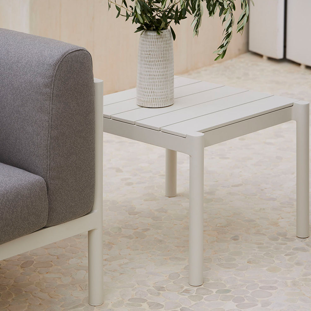 Gray upholstered sofa beside a white wooden coffee table on a textured beige floor.