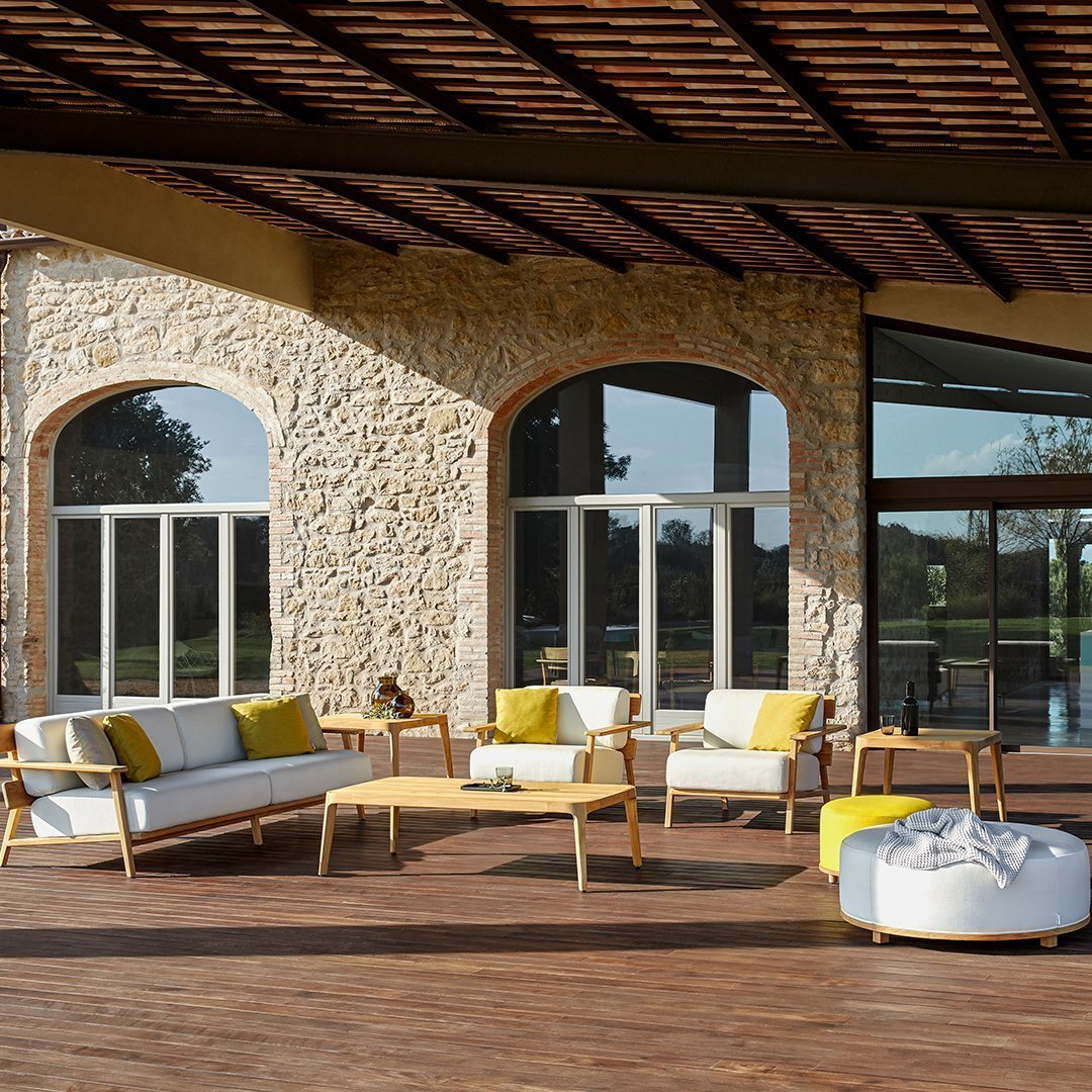 Outdoor seating set featuring white cushions and vibrant yellow accents against a rustic stone backdrop.