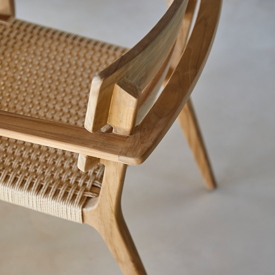 Wooden side table in natural tones, with a white lounge chair and blue water patterns reflecting sunlight.