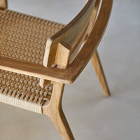 Wooden side table in natural tones, with a white lounge chair and blue water patterns reflecting sunlight.