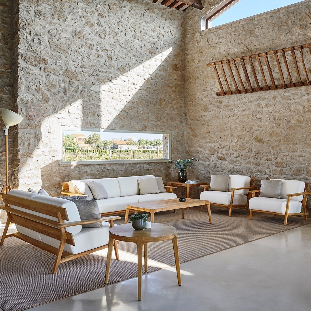 Light beige cushions and natural wood frames on a modern minimalist sofa set in a spacious, bright living area.