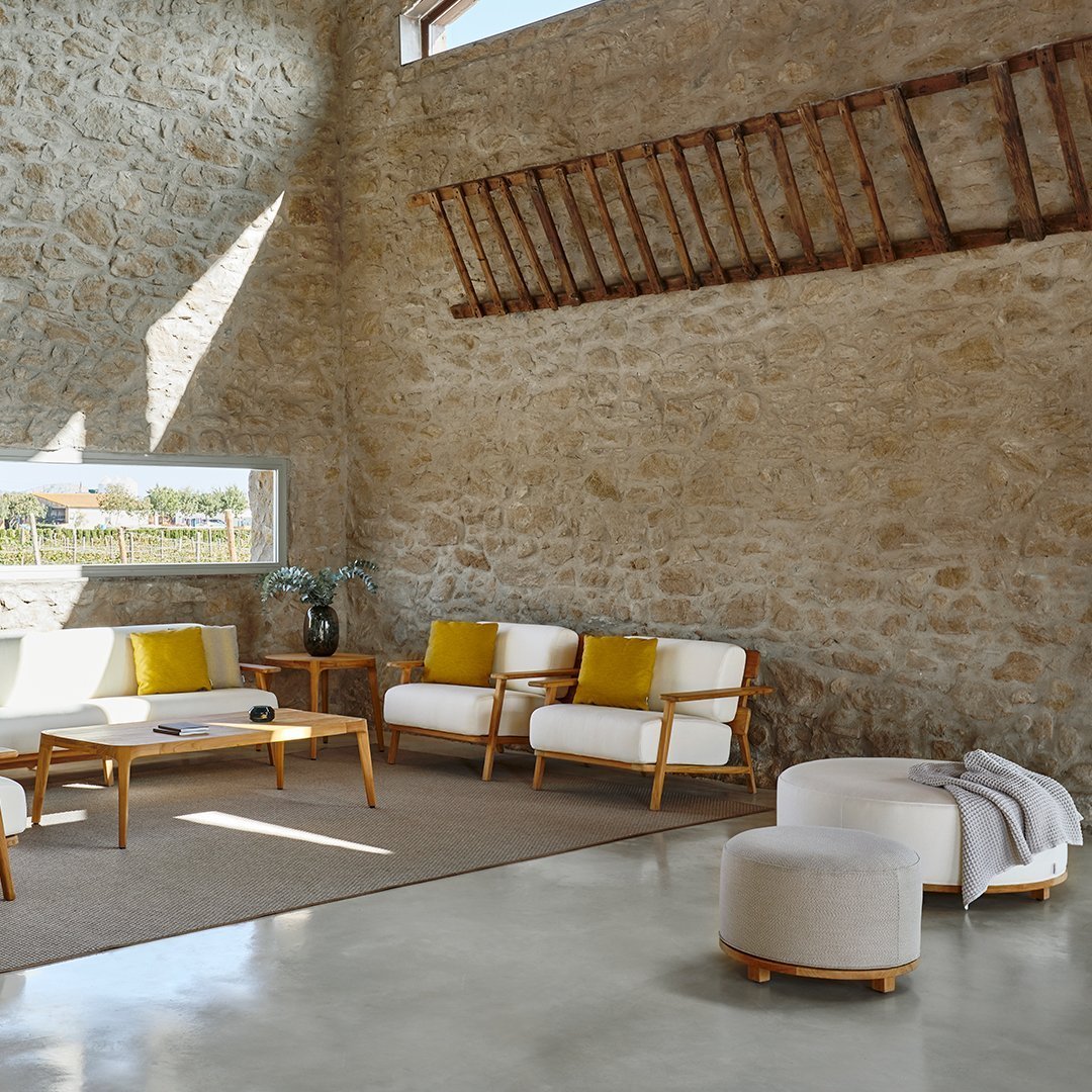 Modern living room with neutral tones, yellow accents, stone walls, and minimalist furniture design.