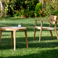 Natural wood table and chair in a serene outdoor setting, showcasing a warm oak tone and minimalist design.