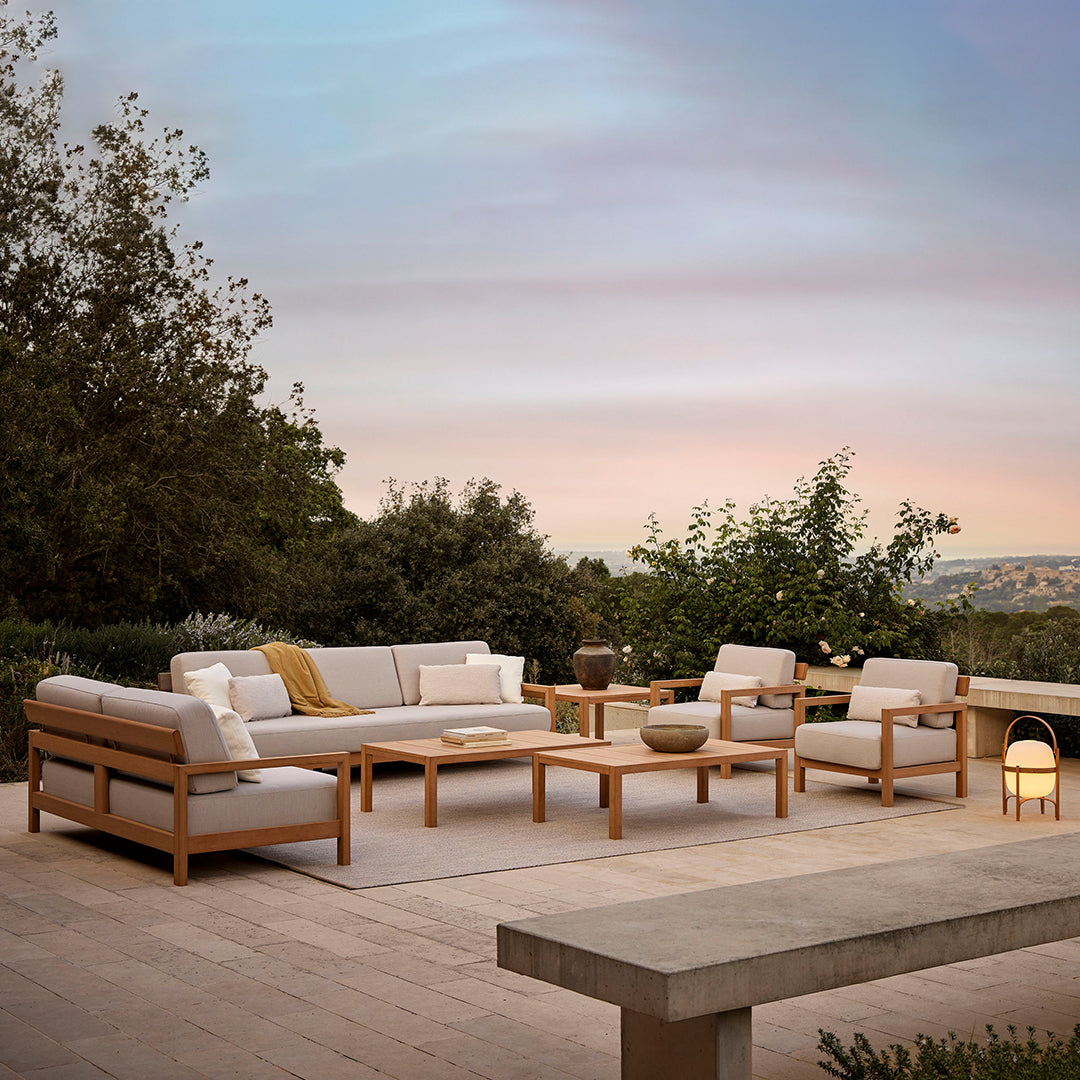 Modern outdoor seating set in soft beige cushions with natural wood accents, complemented by a neutral area rug.