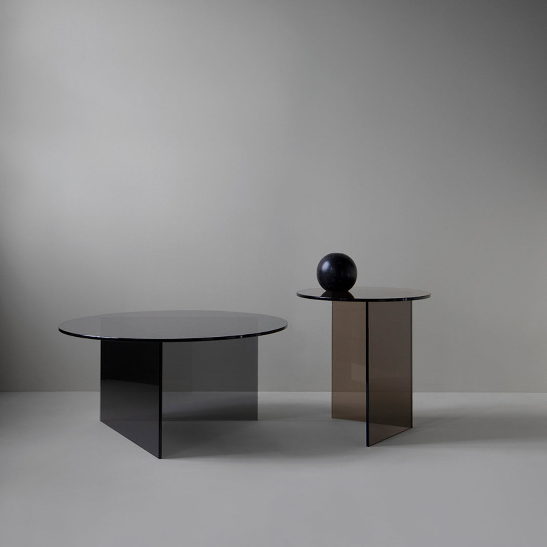 "Modern round tables in sleek black and brown glass with minimalistic designs, perfect for contemporary decor."