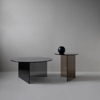 "Modern round tables in sleek black and brown glass with minimalistic designs, perfect for contemporary decor."