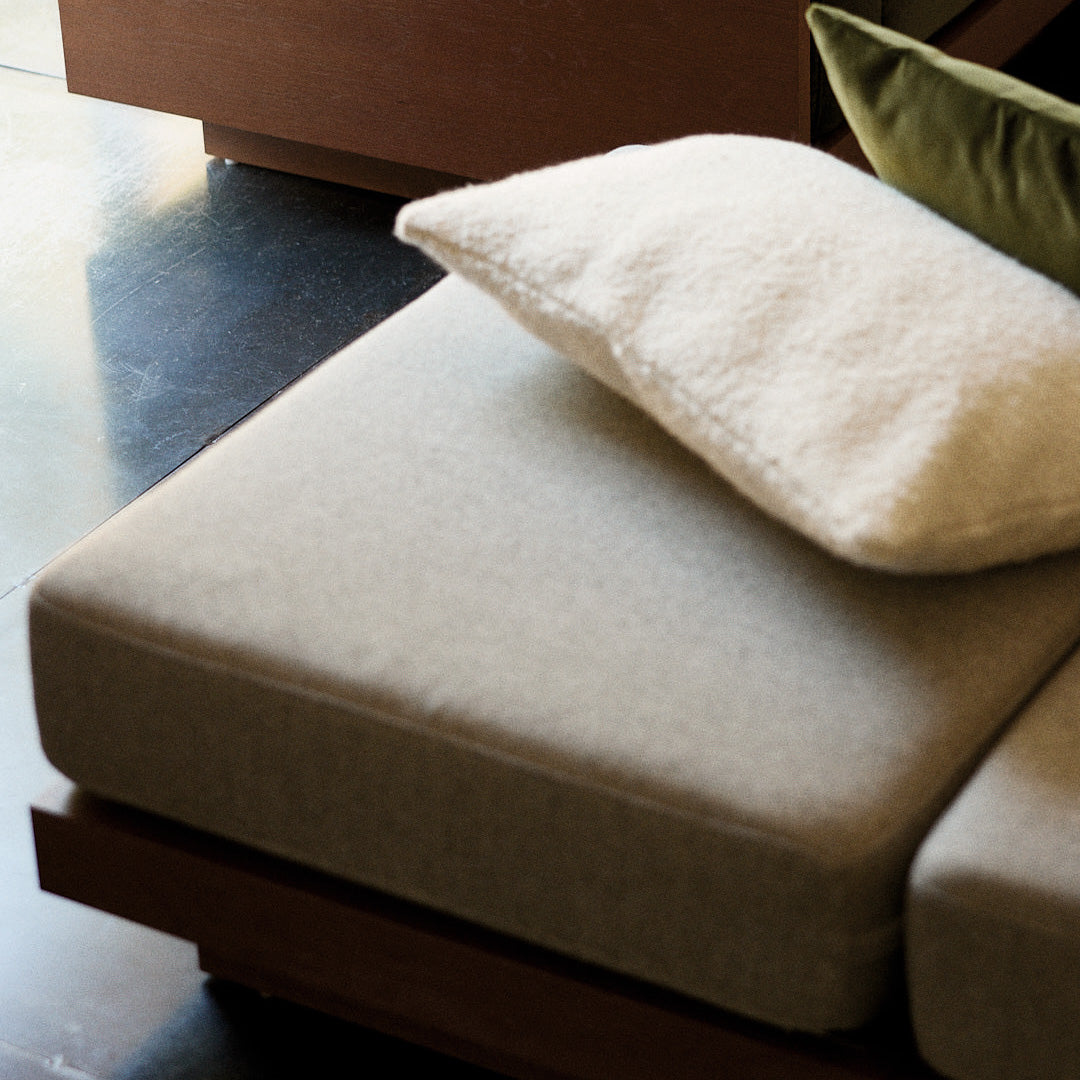 Light gray cushion with a textured cream pillow on a wooden base, featuring soft, neutral tones for a modern look.