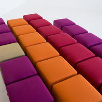 Colorful padded stools in orange, purple, and magenta arranged in a modern geometric pattern.