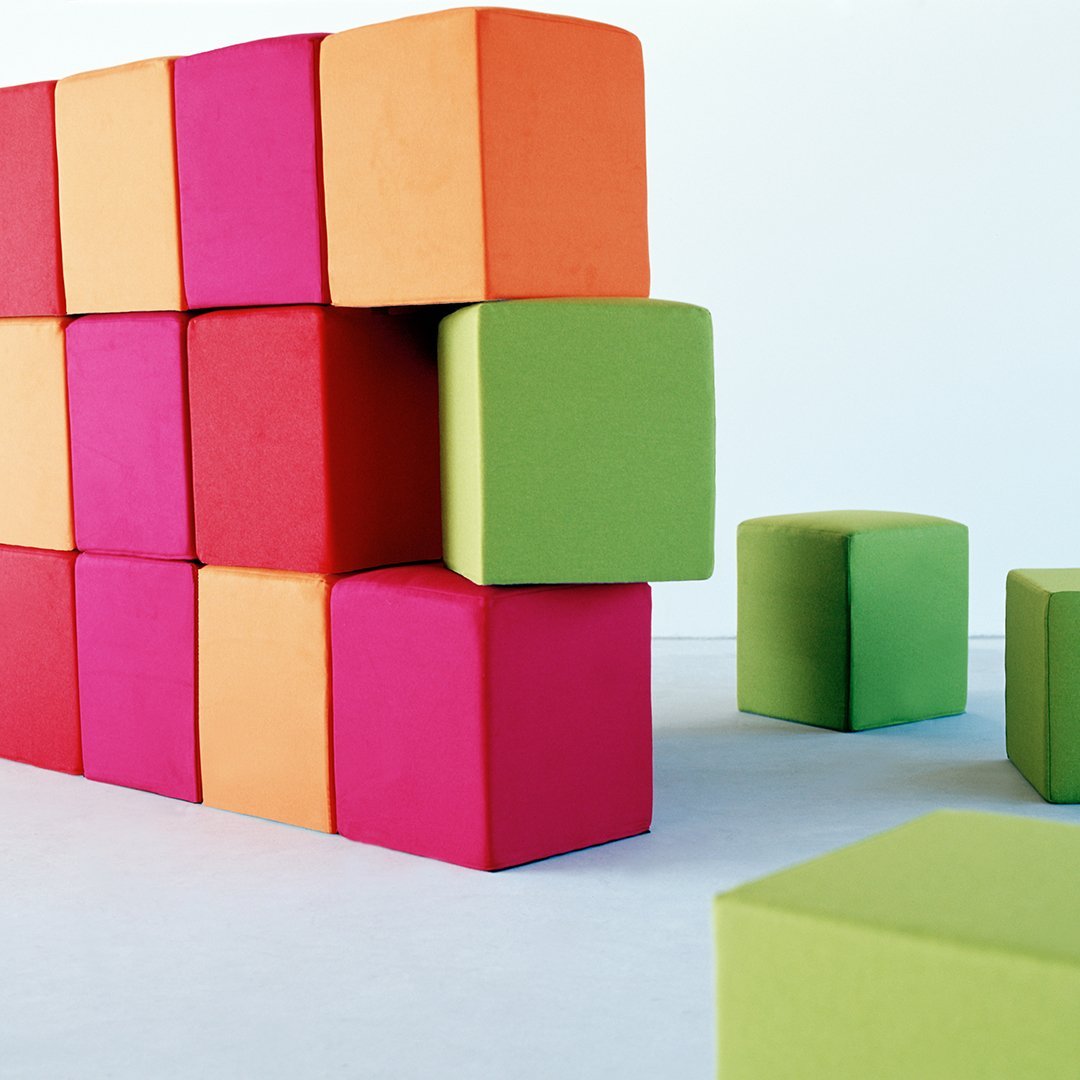 Colorful foam blocks in vibrant pink, orange, and green, arranged in a playful pattern against a white background.