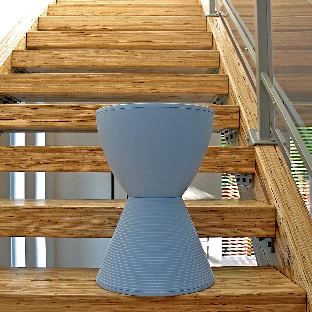 Light blue conical stool with ridged texture, set against natural wood stairs. Modern and stylish home accent.