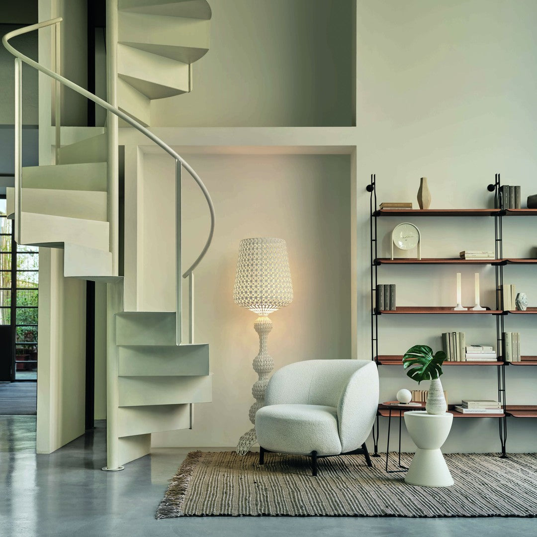 Elegant white spiral staircase, soft beige walls, textured rug, and muted earth tones in furnishings create a serene atmosphere.