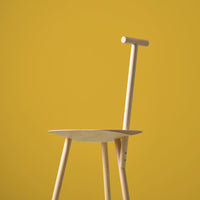 Minimalist wooden chair against a vibrant yellow background, showcasing natural wood tones and clean lines.