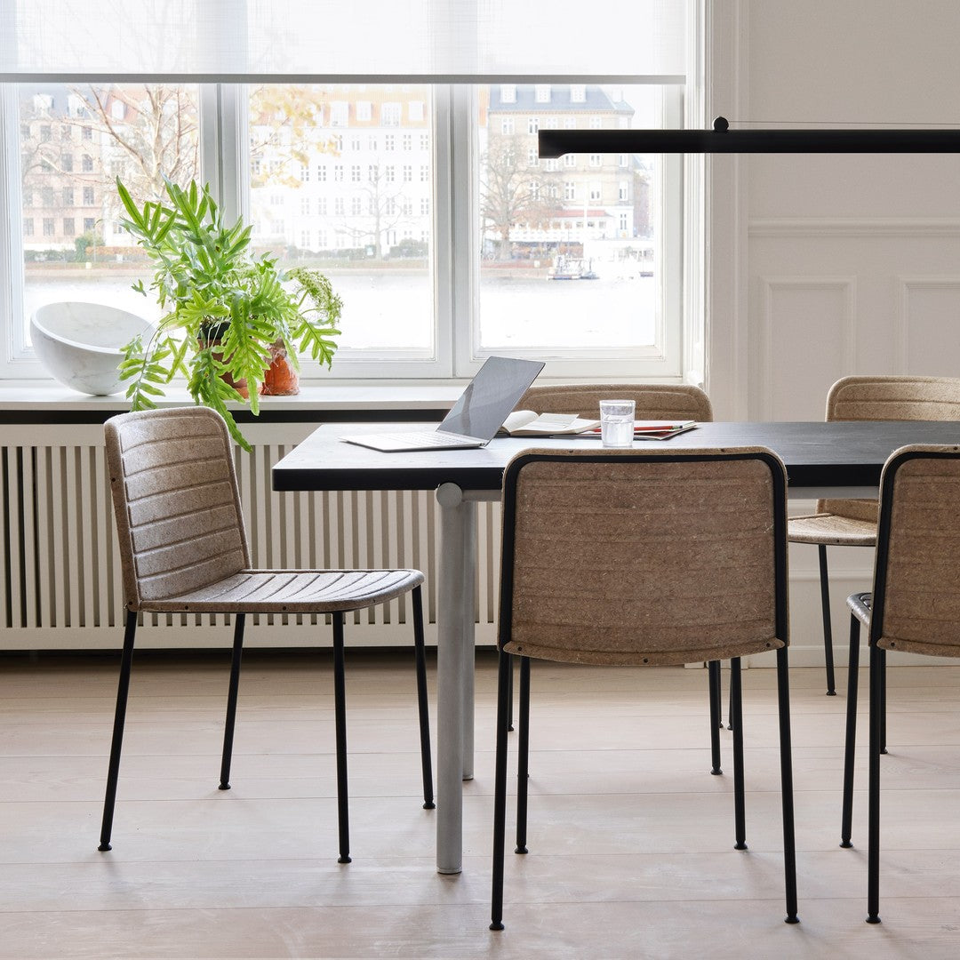 "Minimalist dining set with beige woven chairs and a sleek black table, set against a bright interior backdrop."