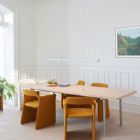 Bright yellow chairs around a light wooden table, complemented by a white pendant light and neutral walls.